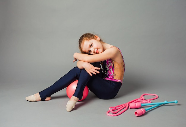 Gymnaste de fille posant avec masse et corde sur fond gris Sports professionnels pour enfants
