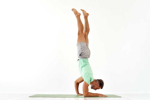 Gymnastique Acrobatique De Jeune Homme Faisant Un Studio De Poirier D'isolement Sur Le Sportif Athlétique Blanc