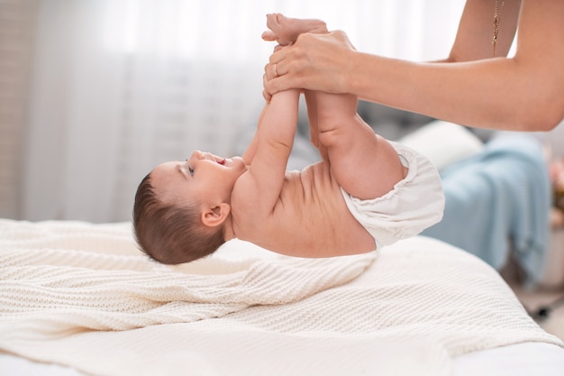 Photo gymnastique pour bébé. une mère soulève son bébé par les bras et les jambes.