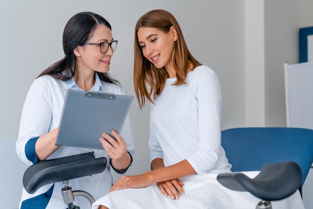 Gynécologue adulte souriante travaillant avec un patient dans une clinique moderne