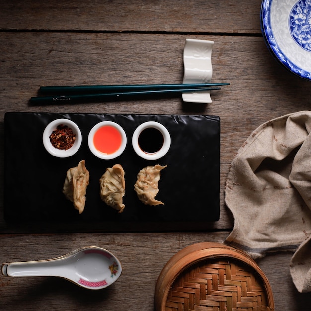 Gyoza, boulette cuite à la vapeur et grillée, servie avec une sauce aux trois sortes sur une assiette en pierre noire