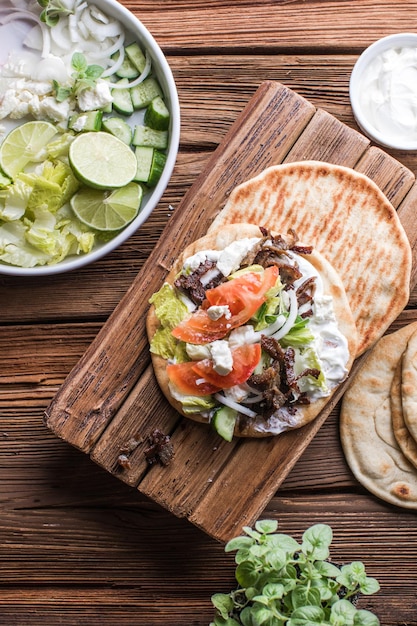 Photo des gyros grecs enveloppés dans des pains pita sur un fond en bois