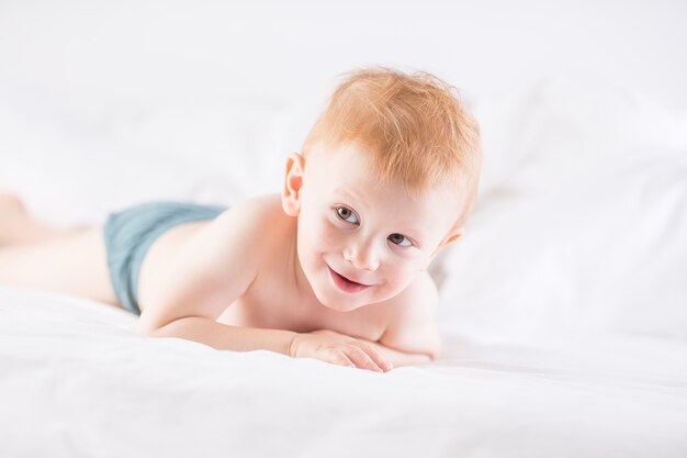 Habby jeune garçon souriant dans un lit blanc.