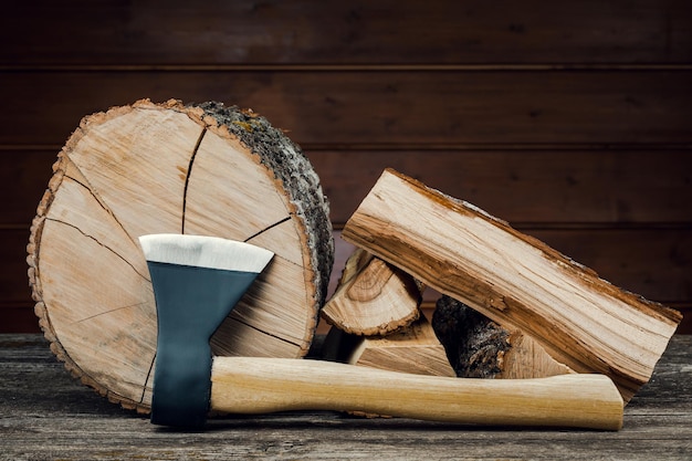 Hache et bois de chauffage, sur fond de planches de bois.