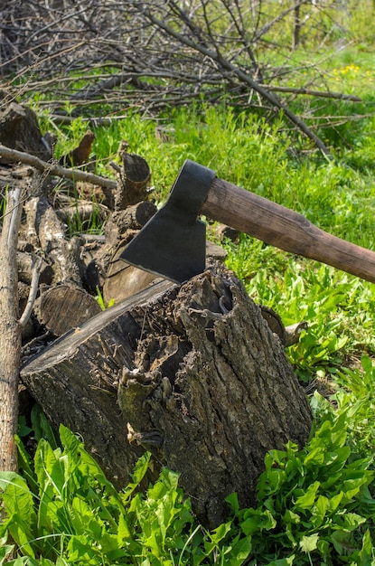 Une hache et une terrasse pour couper du bois de chauffage sur fond d'herbe verte