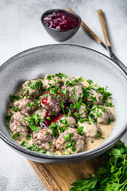 Hacher les boulettes de viande avec une sauce à la crème sur une assiette. Fond en bois blanc. Vue de dessus.