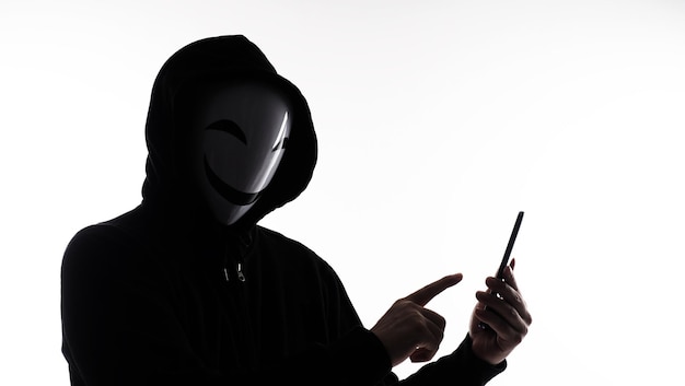 Hacker Anonymous et masque facial avec smartphone à la main