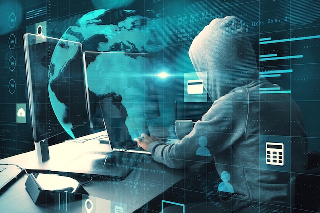 Hacker au bureau avec des moniteurs à l'aide d'un ordinateur portable avec une interface de grille d'hologramme de globe lumineux créatif sur fond flou Transformation numérique piratage innovation et concept futur Double exposition