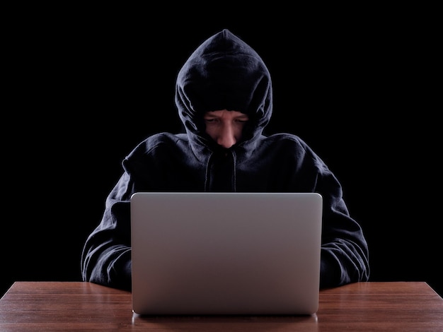 Hacker informatique volant des données à partir d'un ordinateur portable Concept de sécurité du réseau vol d'identité et crime informatique Arrière-plan sombre