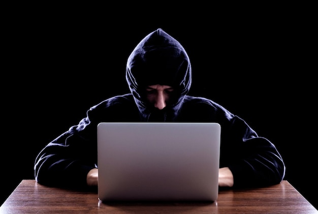 Hacker informatique volant des données à partir d'un ordinateur portable Concept de sécurité du réseau vol d'identité et crime informatique Arrière-plan sombre
