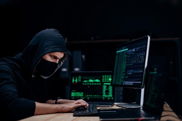 Hacker travaillant en sweat à capuche et masque