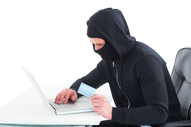 Hacker utilisant un ordinateur portable et une carte de crédit