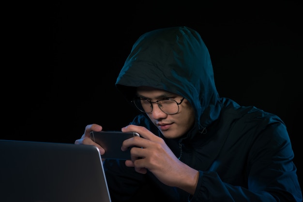 Hacker utilisant un smartphone. Environnement nocturne très sombre