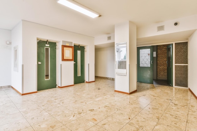 Hall d'entrée d'un immeuble résidentiel avec carrelage beige au sol et entrées d'appartements résidentiels