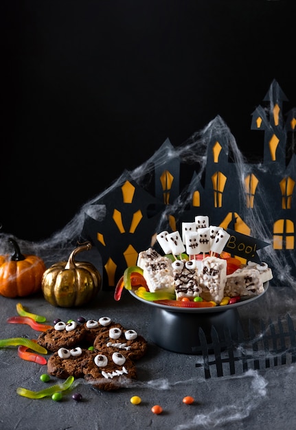 Halloween candy bar monstres drôles faits de biscuits au chocolat et fantômes guimauve gros plan sur la table. Décoration de fête d'Halloween. Tromper ou traiter le concept.