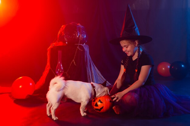 Halloween et célébration concept enfant fille en costume de sorcière avec citrouille d'halloween jouant avec