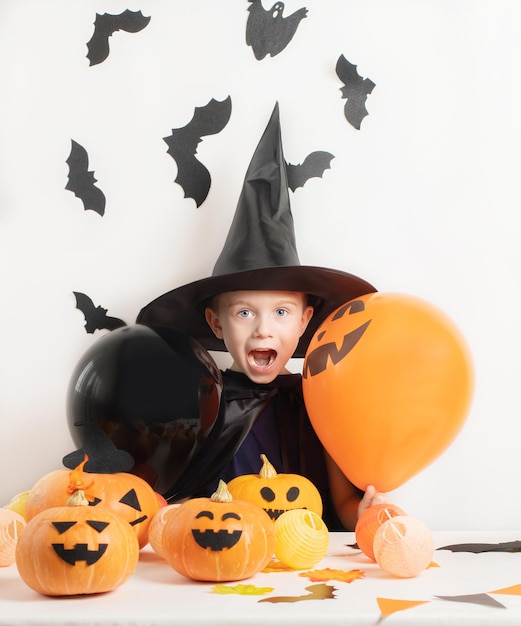 Halloween kids Funny petit garçon portant un chapeau de sorcière avec des ballons orange et noirs Happy Halloween