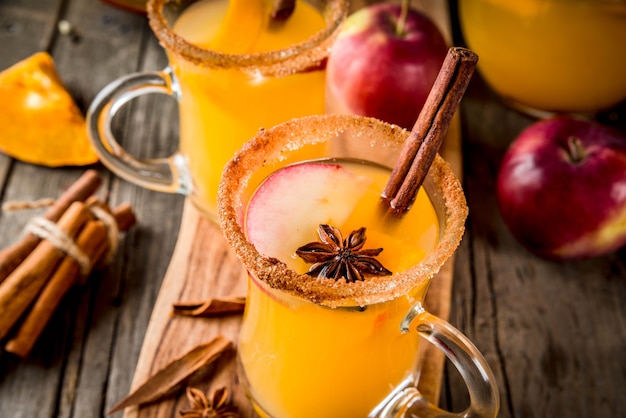 Halloween, Thanksgiving. Automne traditionnel, boissons et cocktails d'hiver. Sangria épicée à la citrouille chaude, avec pomme, cannelle, anis. Sur une vieille table en bois rustique, dans des tasses en verre. Espace de copie de mise au point sélective