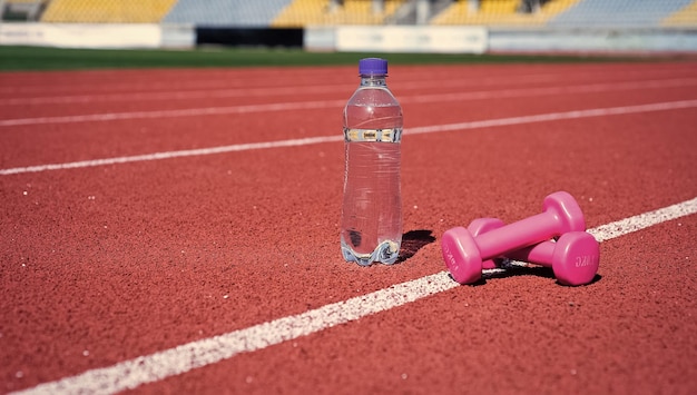 Haltères Et Bouteille Sur La Piste De Course Outil Et équipement De Sport Haltères Sur L'hippodrome Dans Le Stade Hydratation Après La Forme Physique Mode De Vie Sain Et équilibré Maintenir L'équilibre Hydrique Dans Le Corps Pendant L'entraînement