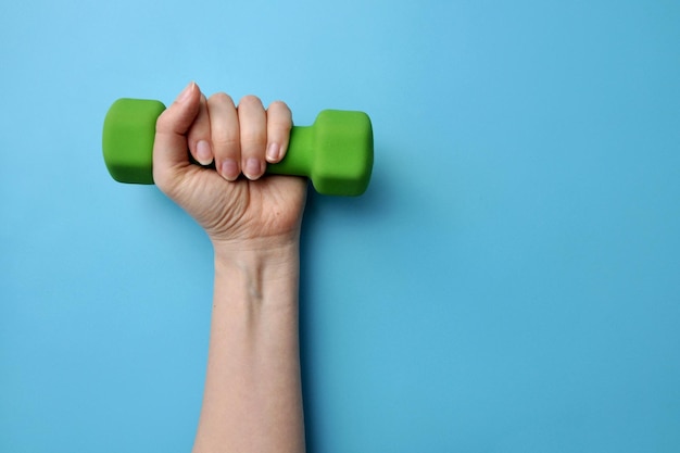 Haltères dans la main d'une femme. Un symbole de la forme physique des femmes