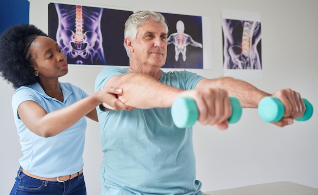 Haltères homme senior et physiothérapie avec une femme noire pour obtenir de l'aide à la clinique pour l'entraînement ou avec l'entraînement Physiothérapie du patient et aide avec une infirmière ou un équipement dans une maison de retraite ou de réadaptation