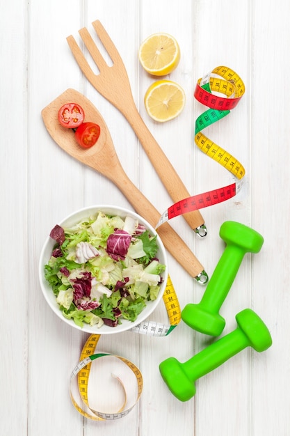 Haltères, ruban à mesurer et alimentation saine. Fitness et santé. Vue d'en haut sur une table en bois