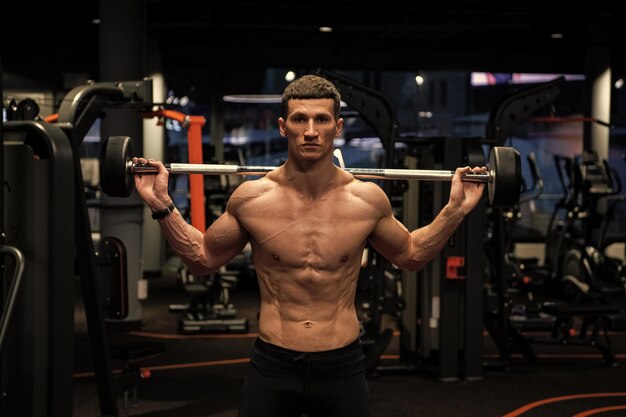 Photo un haltérophile sans chemise soulève une barre dans un gymnase.