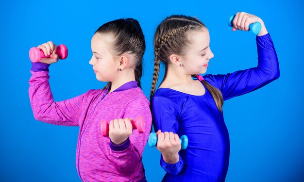 Haltérophilie pour les muscles des soins du corps Soins du corps de l'enfance Régime de remise en forme pour la santé énergétique Enfants heureux avec haltères Entraînement de succès sportif des petites filles tenir le concept de soins du corps haltères