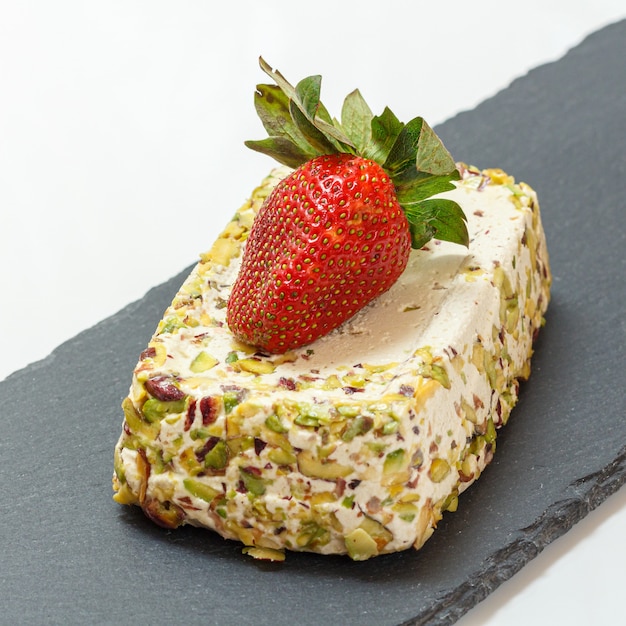 Halva aux pistaches et fraise sur une planche à découper en pierre.