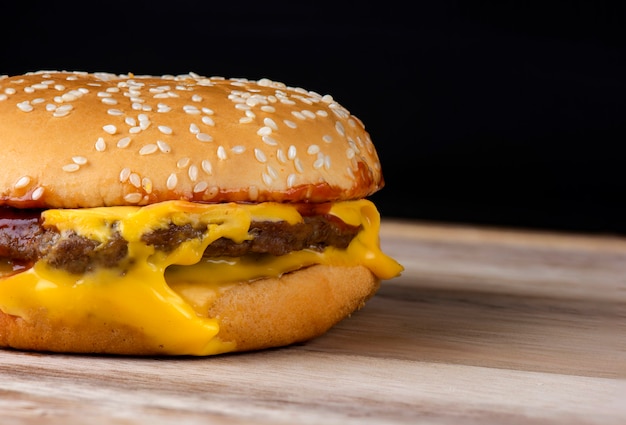 Hamburger au fromage sur une table en bois avec un fond noir