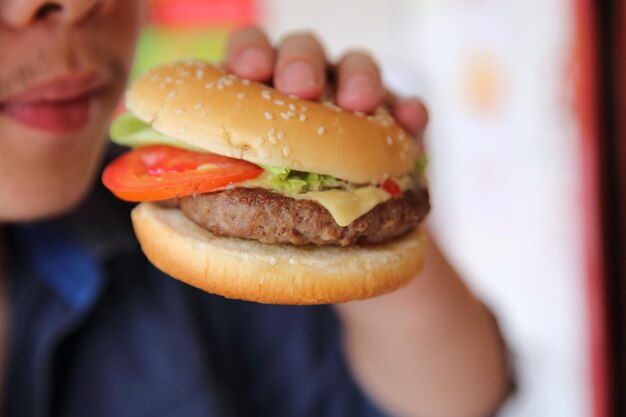 Hamburger de boeuf mangeant sur une main d'homme en gros plan