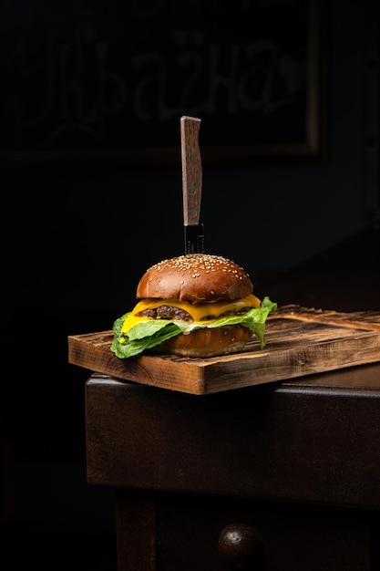 Un hamburger avec un couteau sur une planche de bois