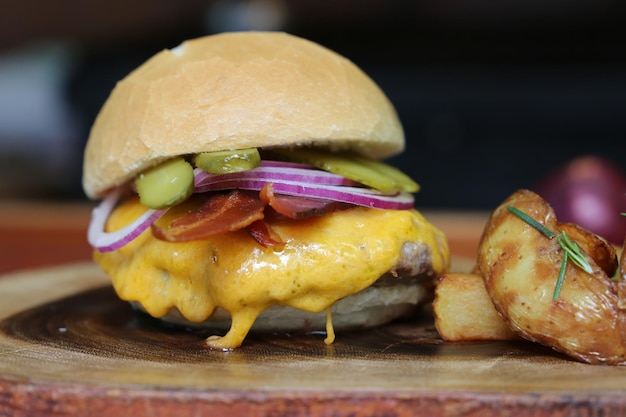 Hamburger fait sur la grille du barbecue avec cornichon fromage bacon oignon sur fond de bois