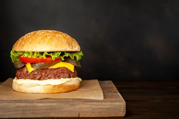 Photo hamburger fait maison avec laitue, tomate, fromage et concombre sur une planche à découper avec espace de copie pour votre texte