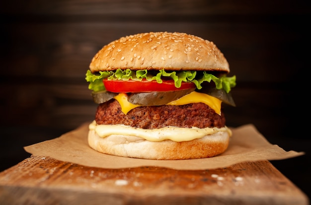 Hamburger fait maison avec laitue, tomate, fromage et concombre sur une planche à découper