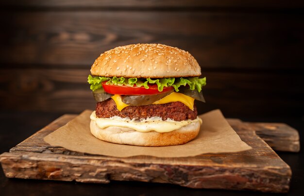 Hamburger fait maison avec laitue, tomate, fromage et concombre sur une planche à découper