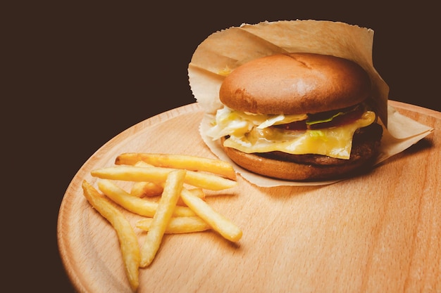 Hamburger frais et savoureux avec du porc et des frites sur une table en bois Traitement photo vintage