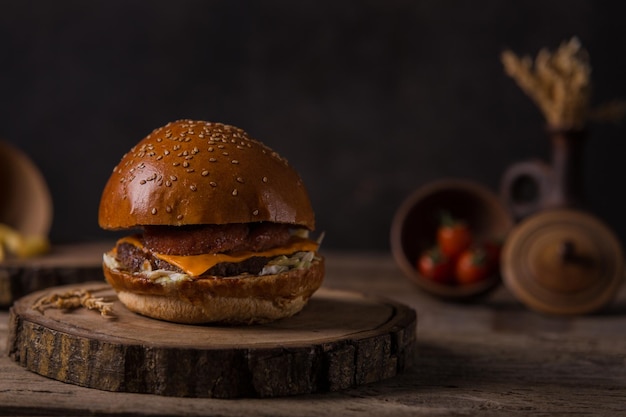 Hamburger avec frites, ketchup, moutarde et légumes frais sur une planche à découper en bois.