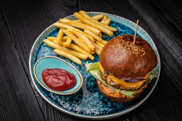 Hamburger avec frites et sauce sur une table en bois foncé