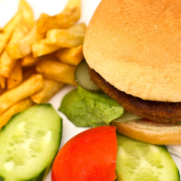 Hamburger avec des frites, des tranches de concombre et des tomates