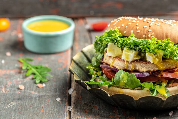 Hamburger avec fromage feta et boeuf de poulet sur une table en bois. symbole de la tentation diététique entraînant une alimentation malsaine. place pour le texte.