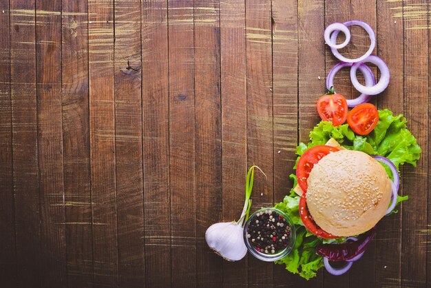 Hamburger avec fromage viande tomates et oignons et herbes sur fond de bois Vue de dessus Espace libre