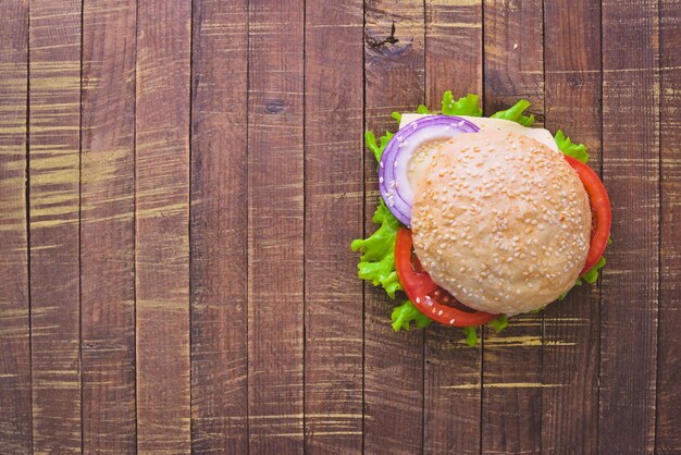 Hamburger avec fromage viande tomates et oignons et herbes sur fond de bois Vue de dessus Espace libre