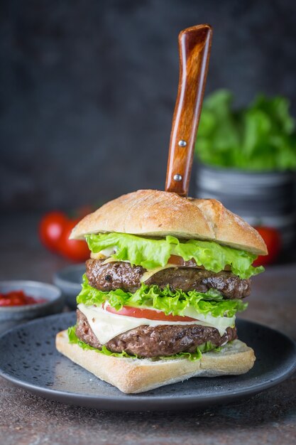 Hamburger avec hamburger de viande de boeuf et légumes frais sur fond sombre. Restauration rapide savoureuse.