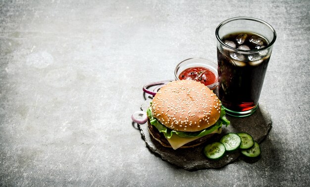 Hamburger avec ketchup et soda sur la table en pierre.