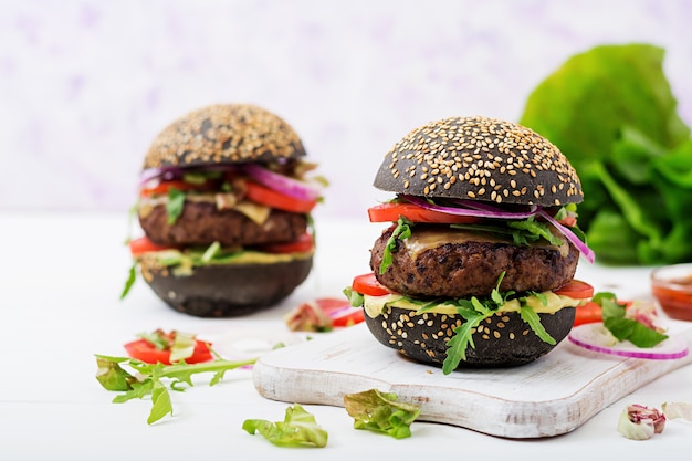 Photo hamburger noir avec hamburger de bœuf juteux, fromage, tomate et oignon rouge