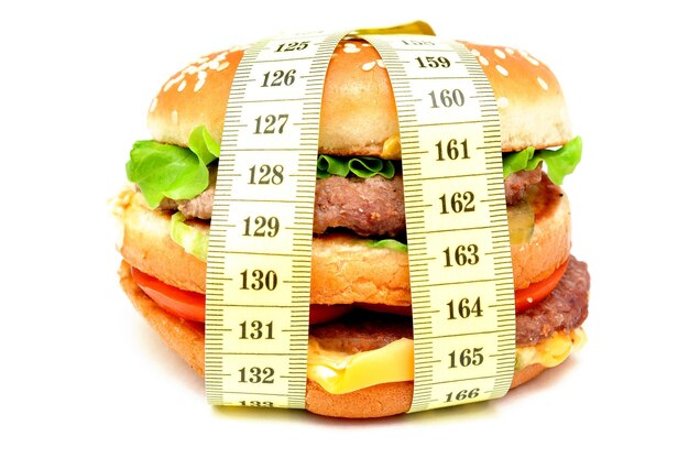 Photo un hamburger et un ruban à mesurer sur un fond blanc