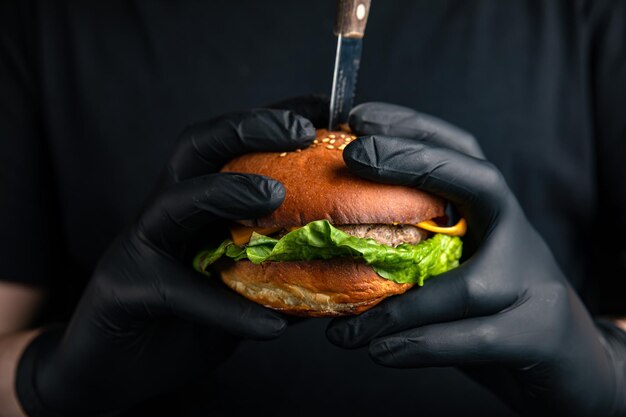 Photo hamburger avec salade de côtelettes de fromage tomate dans les mains