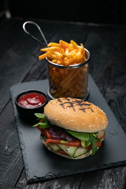 Hamburger avec sauce et frites sur une table en bois foncé