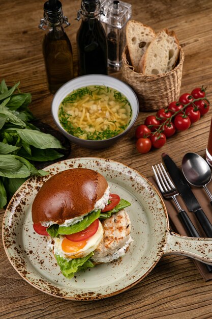 Hamburger avec soupe d'escalopes de poulet jus de tomate tomates basilic sur la table